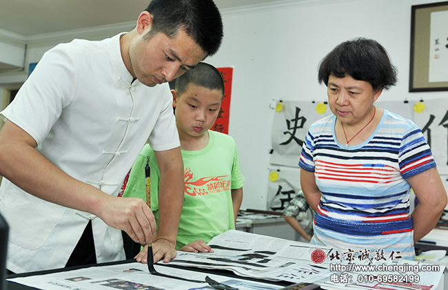 好學的郭阿姨認真觀察劉老師的示范，體會如何掌握書法的力道